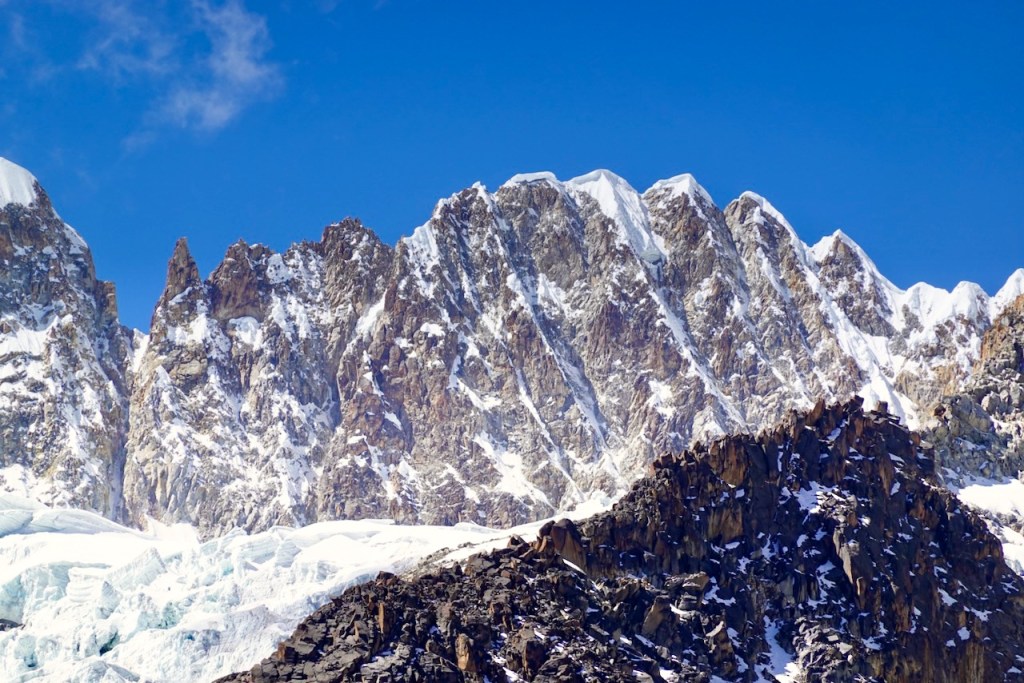 Snow-capped mountain peaks under a clear blue sky, showcasing jagged rock formations and glaciers.