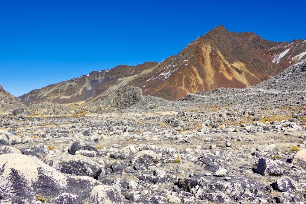 Barren rocky landscape with distant mountains under a clear blue sky.