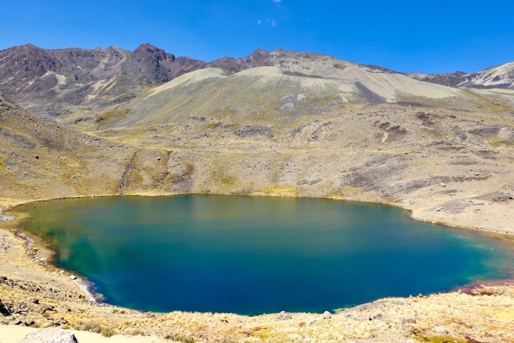 A scenic view of a tranquil lake surrounded by rugged mountains under a clear blue sky.