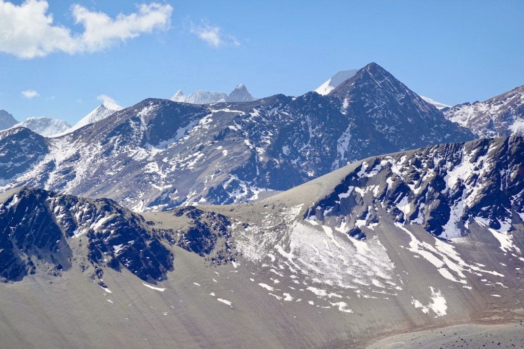 A panoramic view of rugged mountains with snow-capped peaks under a clear blue sky.
