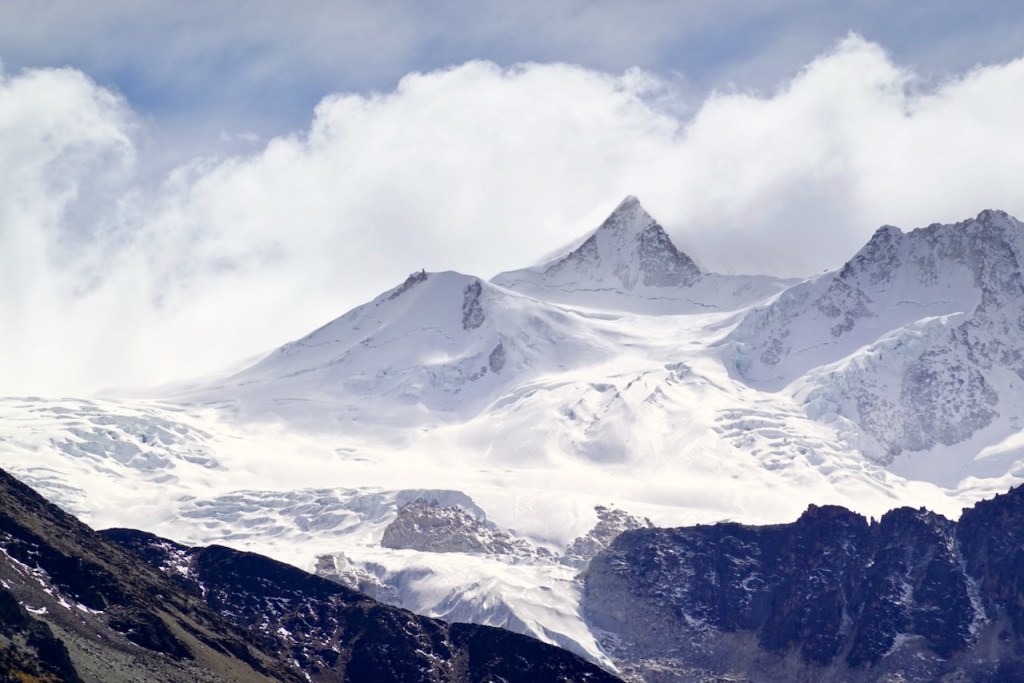 Snow-covered mountain peaks under a cloudy sky.