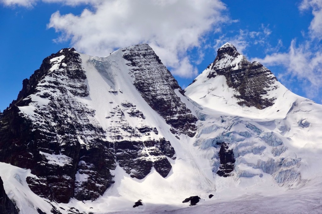 Snow-capped mountains under a blue sky with clouds.