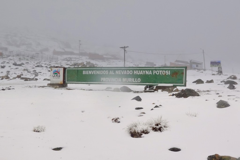 Welcome sign to Nevado Huayna Potosi in the Province of Murillo, surrounded by snow and fog.