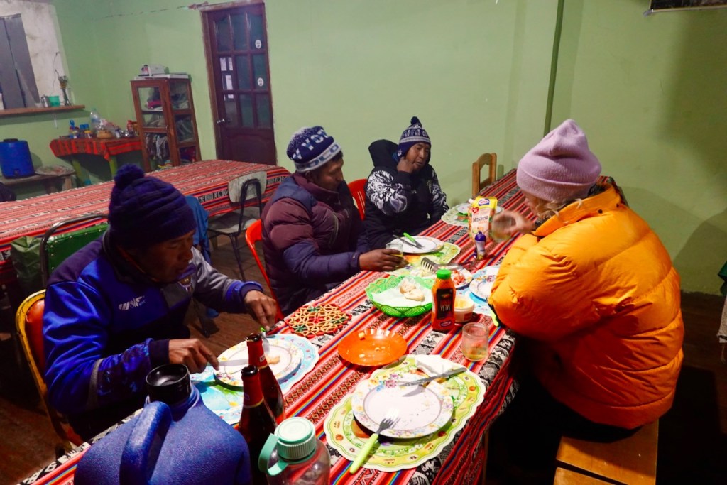 Group of four people sitting around a brightly colored table enjoying a meal together in a cozy indoor setting.
