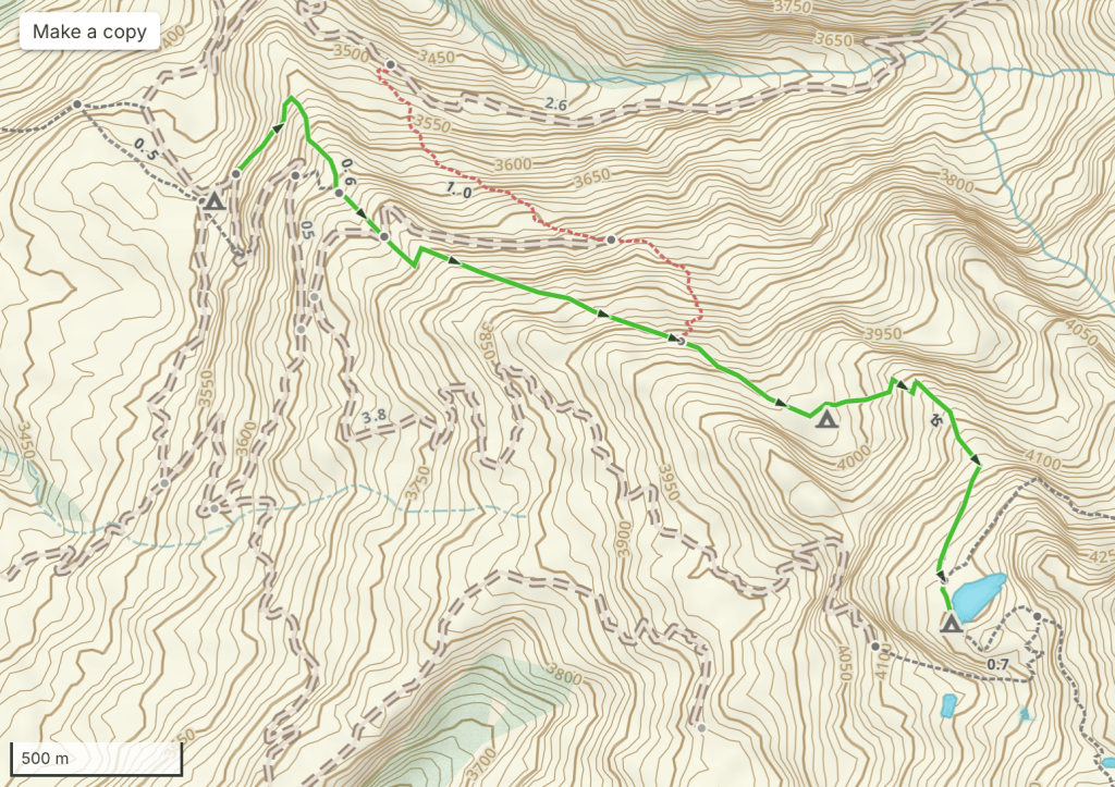 Topographic map showing a hiking trail with elevation contours, marked paths, and a small body of water.